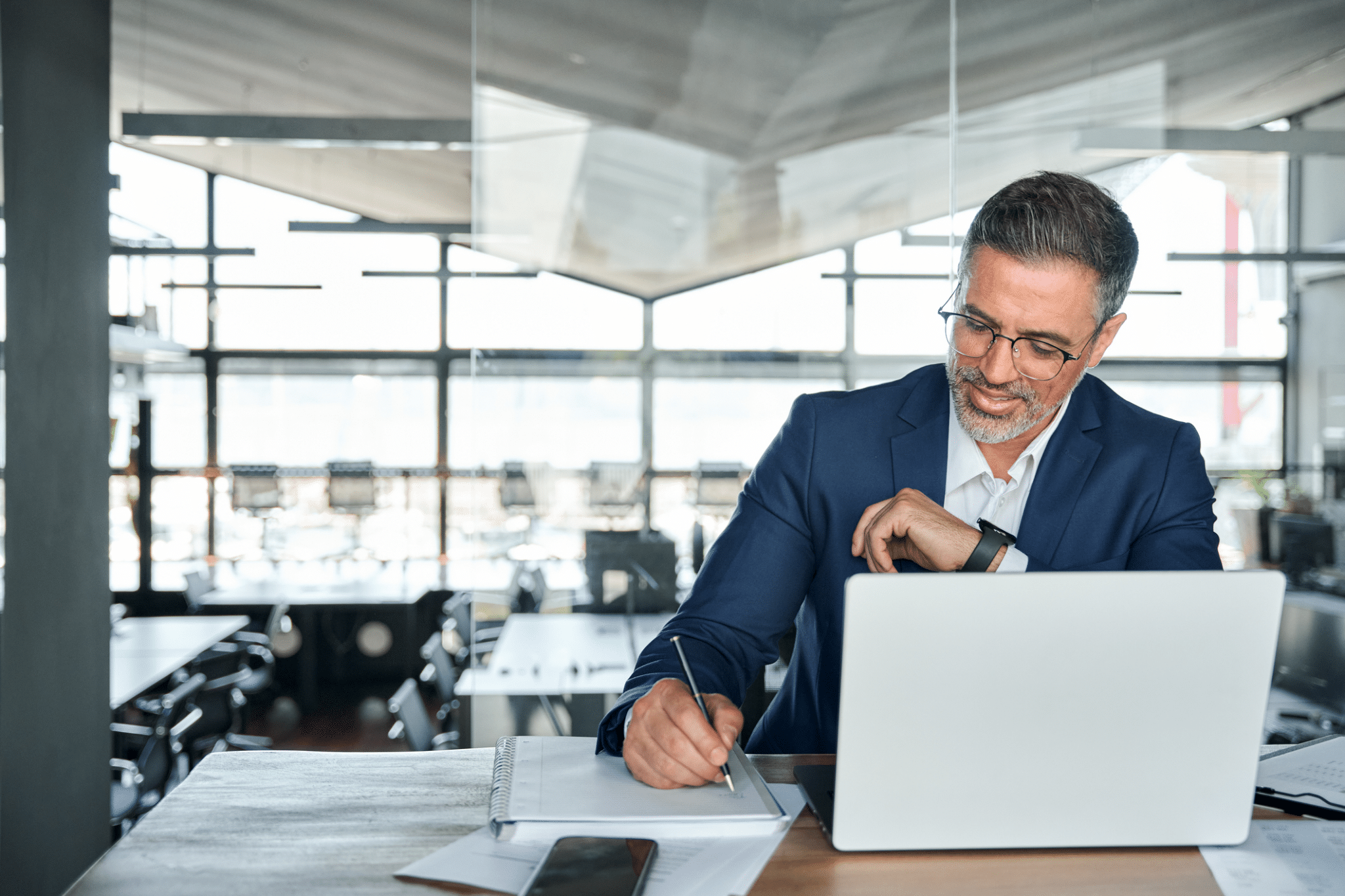 Businessman happily working at laptop in office (financial data security).