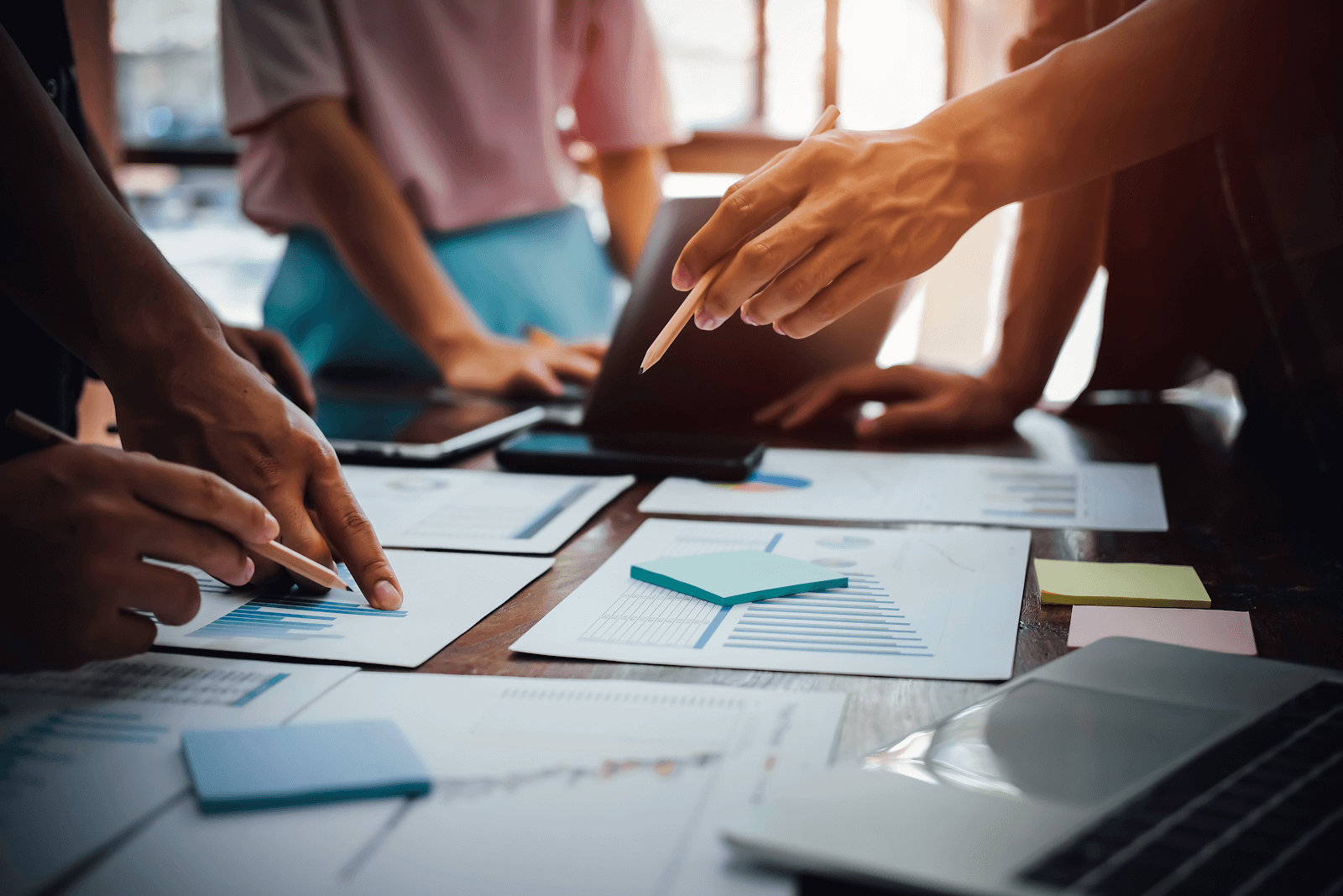 Three professionals at a table with papers and sticky notes (financial consolidation)