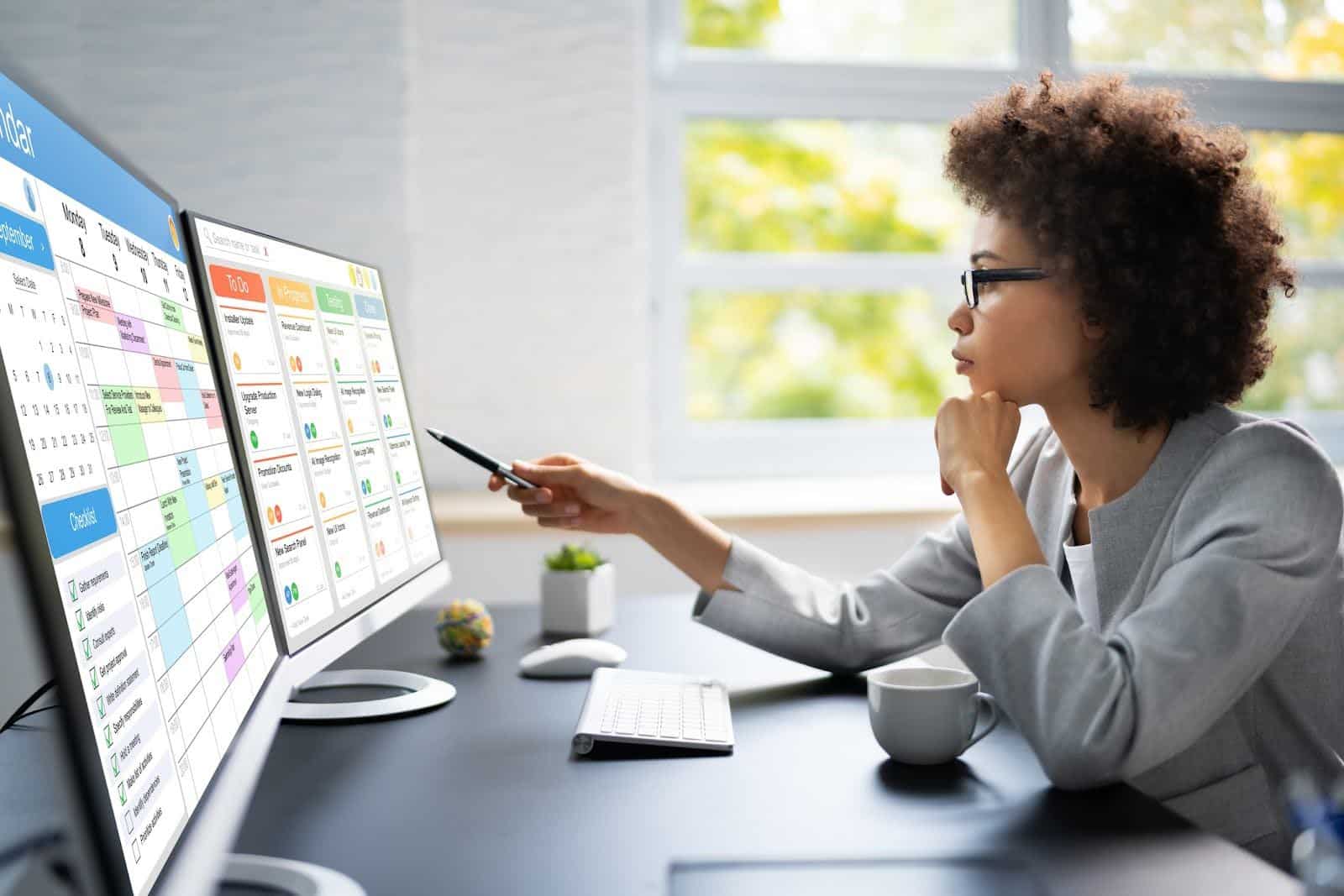 Professional Woman Looking at Data on Two Screens