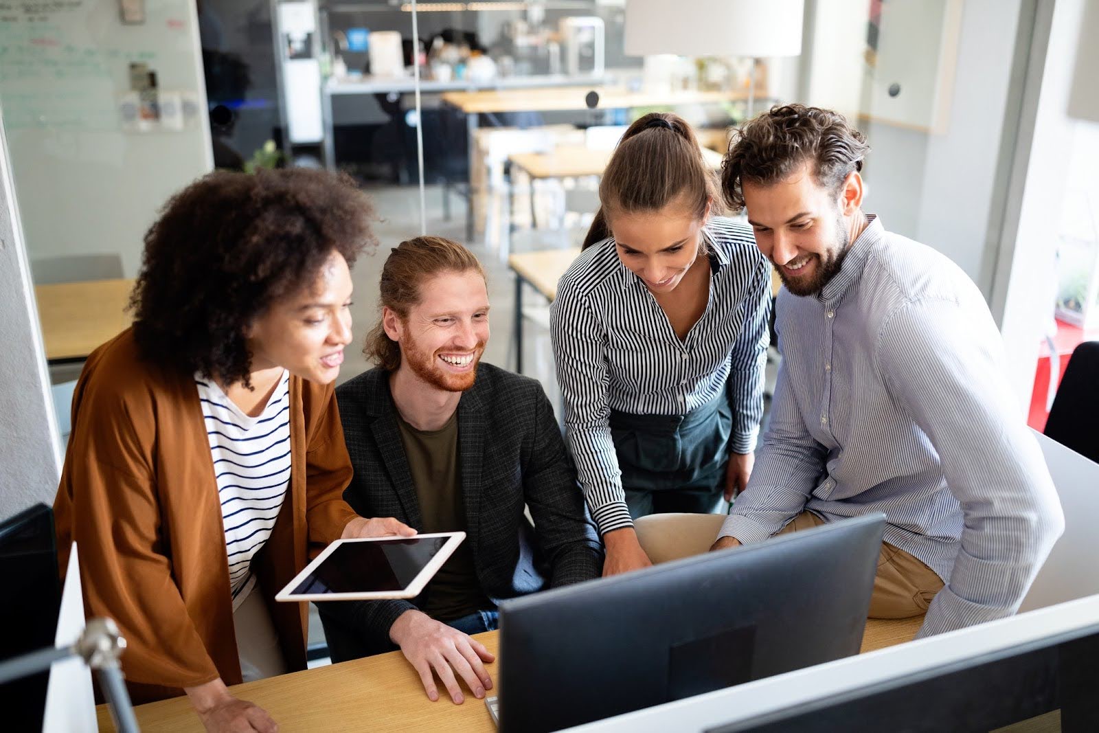 Young professionals gather around computer looking at Sage for charities