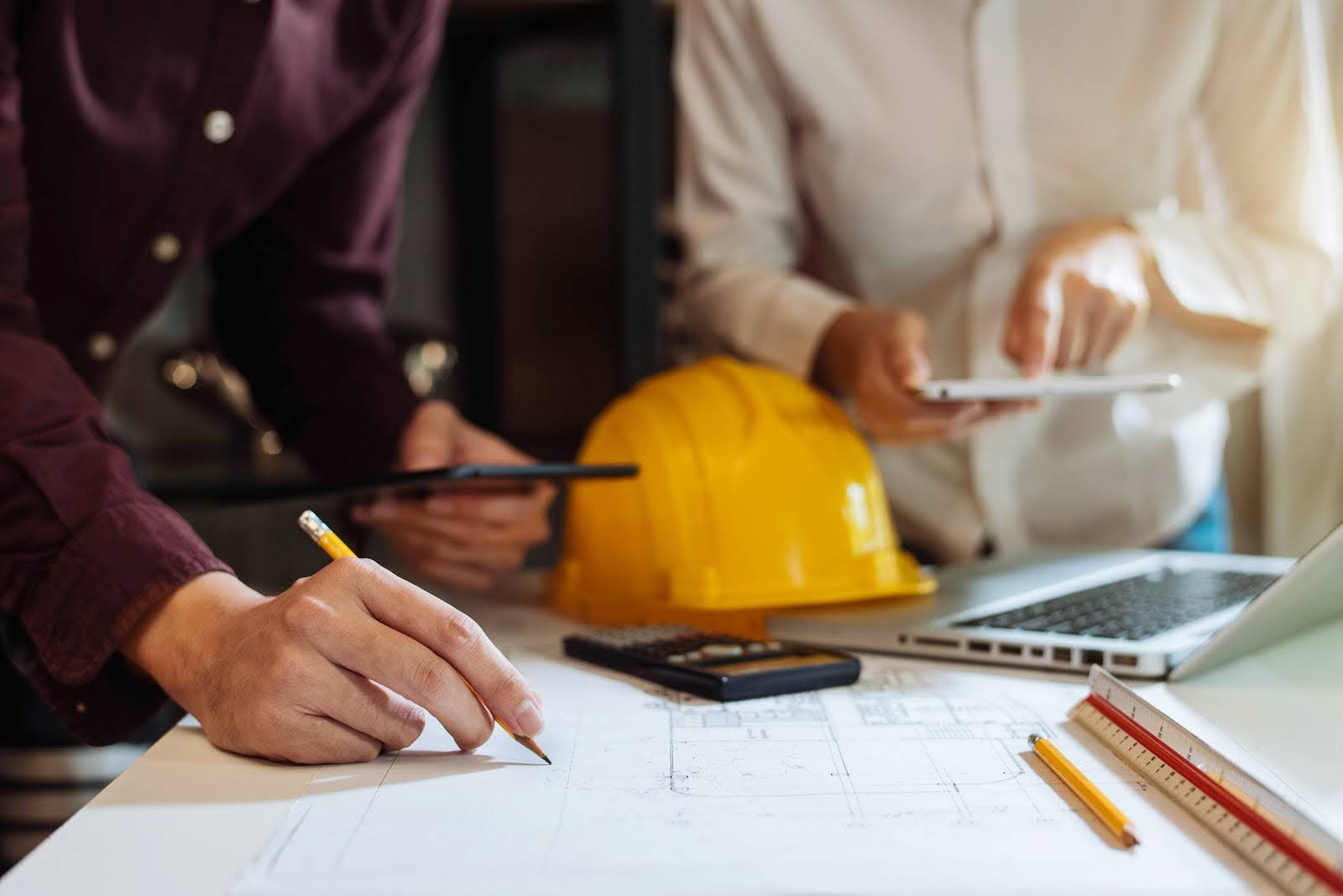 Team working on construction crm at table with laptop and calculator