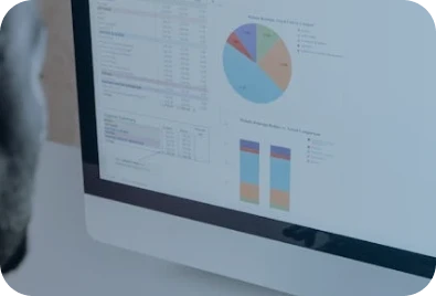 A computer screen displaying financial data, including a colorful pie chart and bar graphs, with spreadsheets and numerical tables visible.