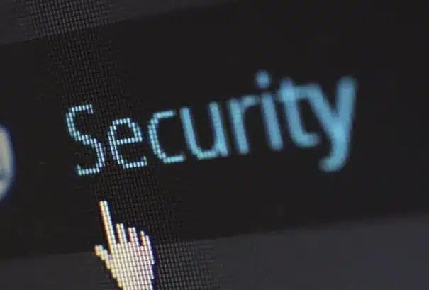 A computer screen displays the word "Security" in blue text, with a white cursor shaped like a hand pointing to it.