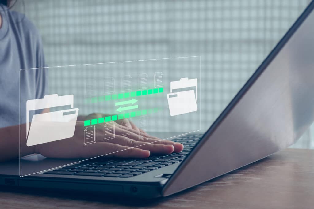 A person types on a laptop keyboard, with a digital graphic overlay showing folders and files transferring between them, symbolizing file sharing or data transfer by Sage Intacct partners.