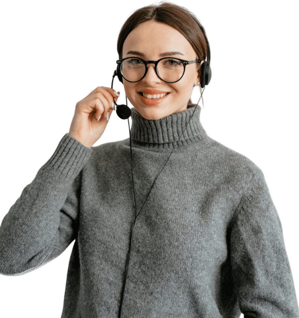 A smiling woman wearing glasses and a gray sweater uses a headset with a microphone, ready to assist you with project cost management software, standing against a plain white background.