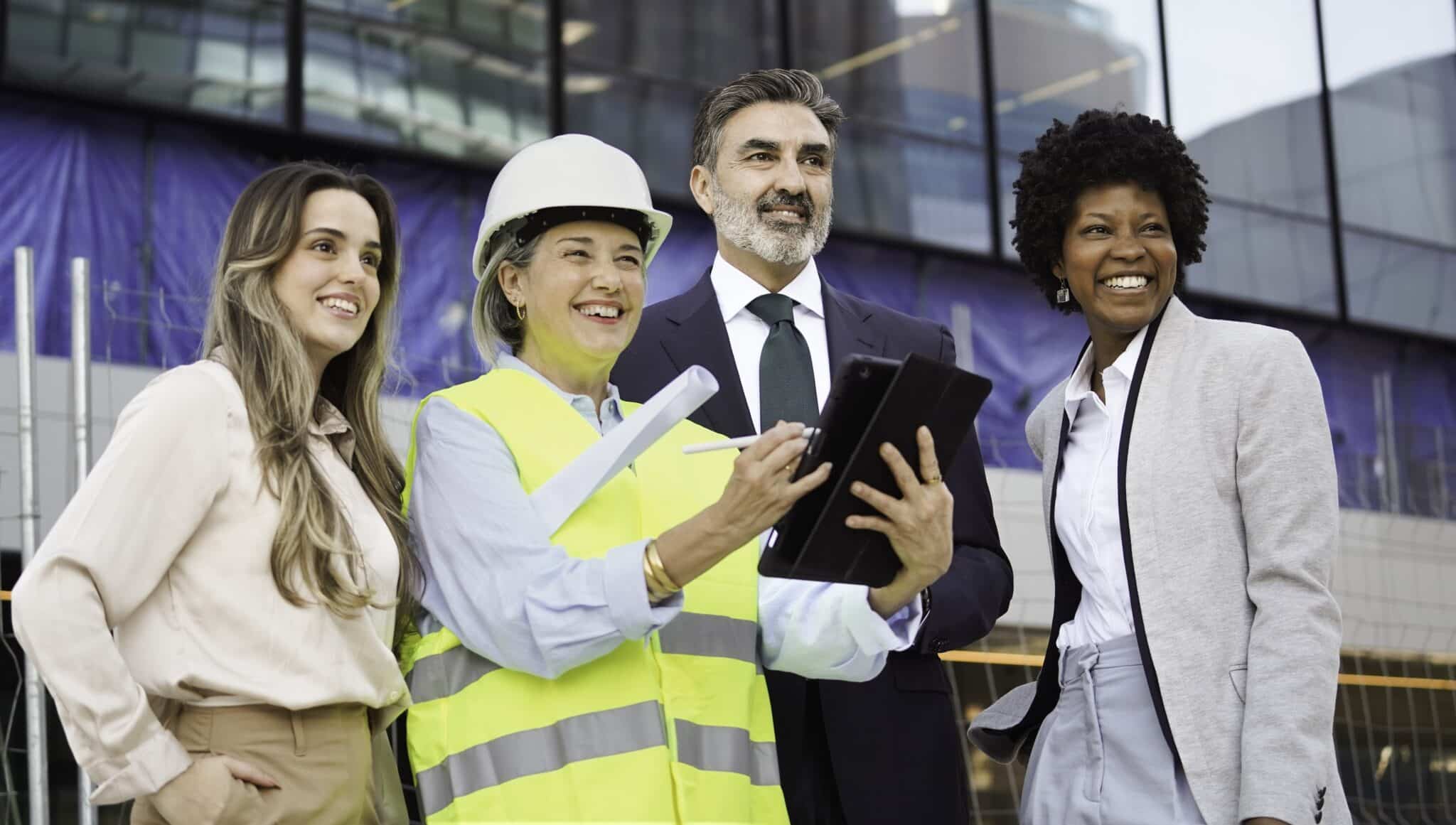 Architect using digital tablet with investors and businesswomen, discussing the change order management process.