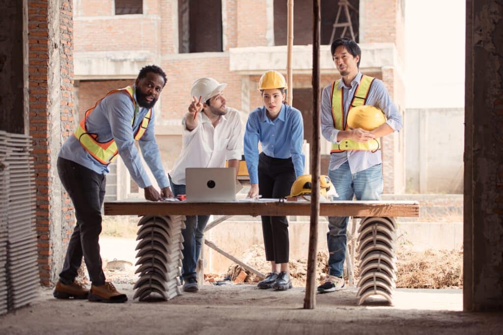 Group of architects and engineers work together to assess the residential home construction site's progress