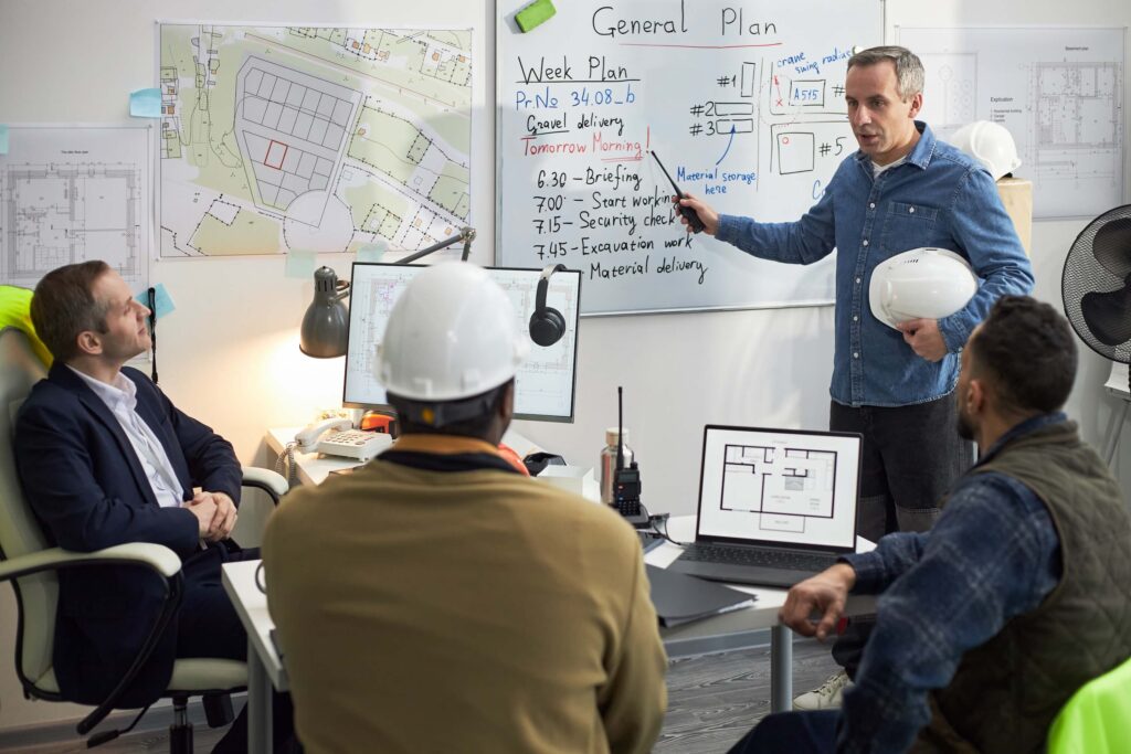 Construction team discussing planned vs actual progress during project planning meeting