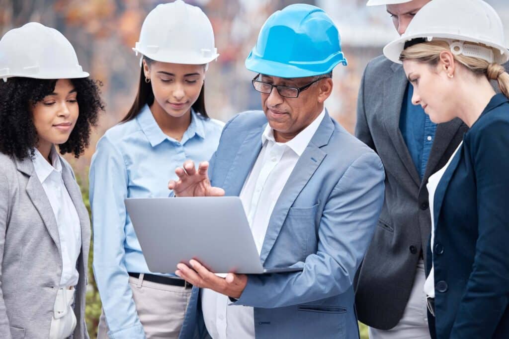 Project team reviewing planned vs actual data on a laptop at a construction site